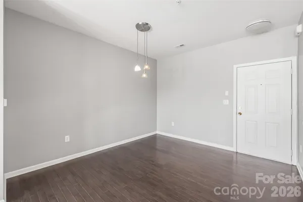 a view of an empty room with wooden floor and a ceiling fan