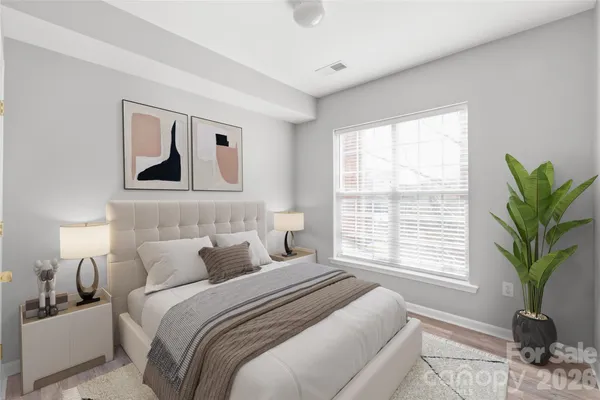 a bedroom with a large bed a couch and a potted plant