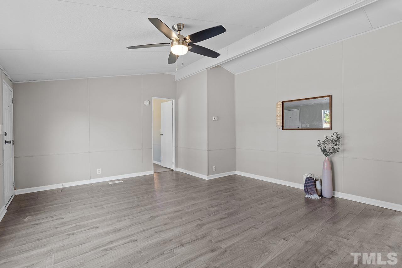 3208 State Road 2750 Willow Spring, NC 27592 - Photo 12 of 32 an empty room with wooden floor a ceiling fan and windows