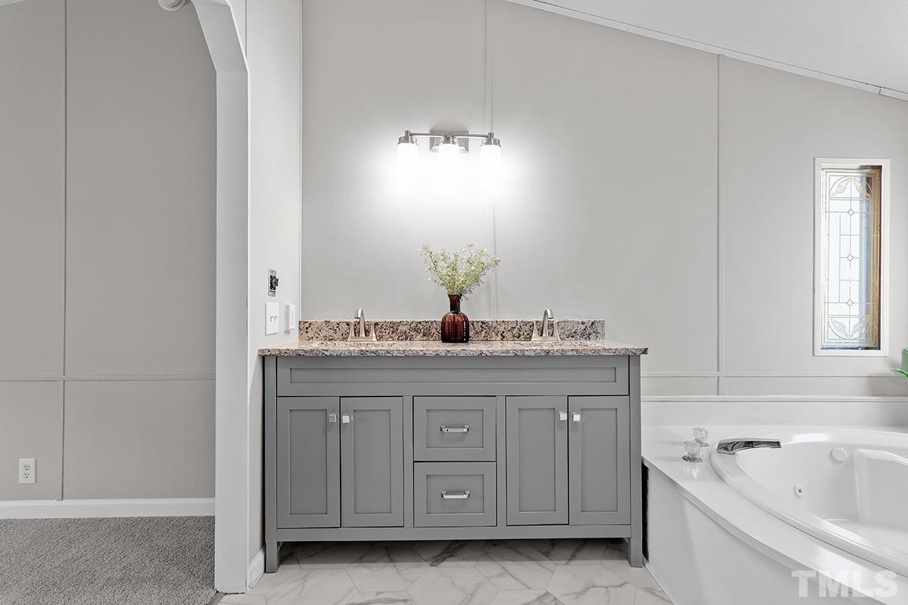 3208 State Road 2750 Willow Spring, NC 27592 - Photo 19 of 32 a bathroom with a granite countertop sink a mirror and a bathtub