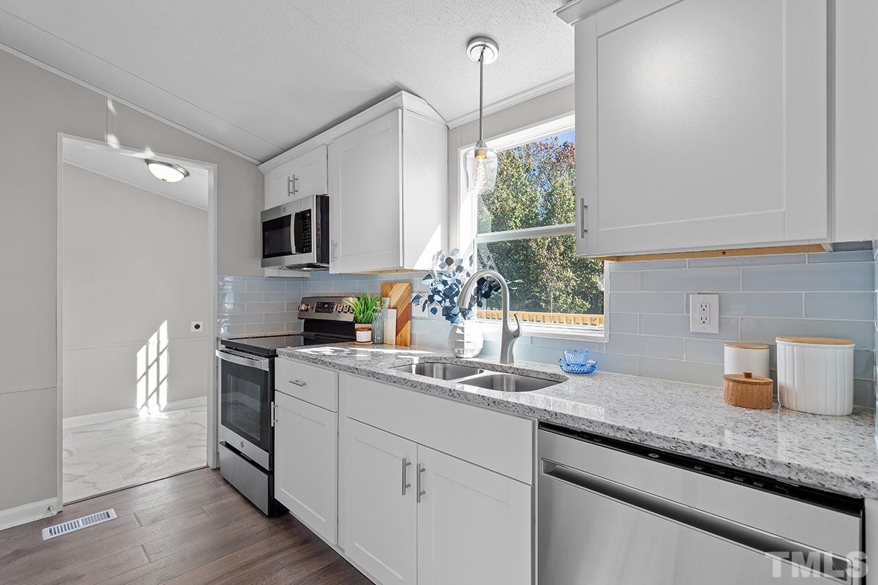 3208 State Road 2750 Willow Spring, NC 27592 - Photo 2 of 32 a kitchen with granite countertop a sink and white cabinets