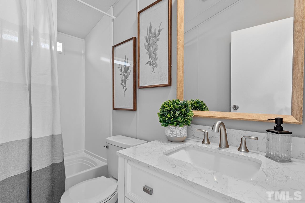 3208 State Road 2750 Willow Spring, NC 27592 - Photo 23 of 32 a bathroom with a granite countertop sink a toilet a mirror and shower