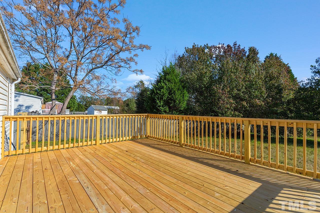 3208 State Road 2750 Willow Spring, NC 27592 - Photo 27 of 32 a balcony with wooden floor and trees in the background