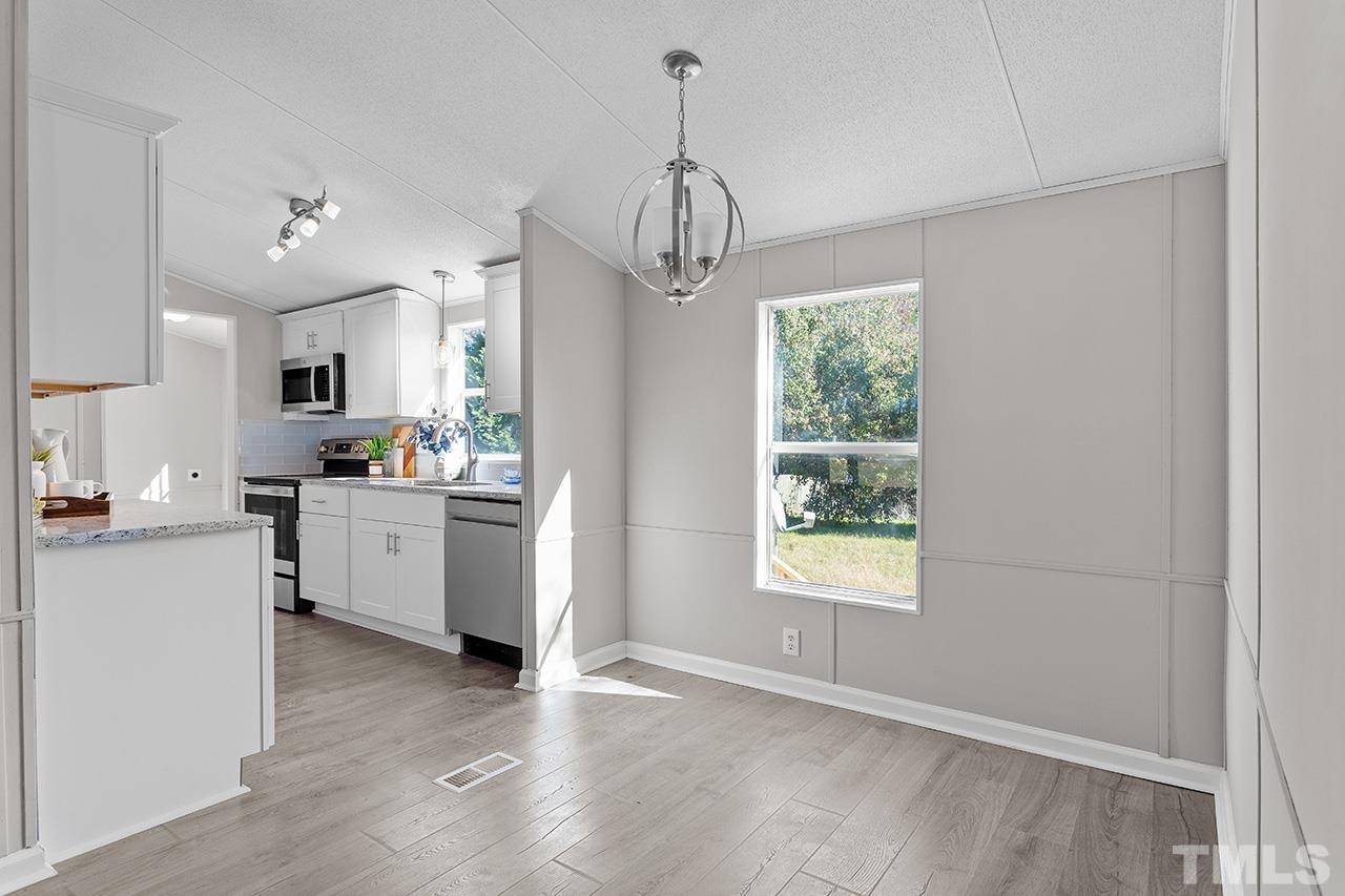 3208 State Road 2750 Willow Spring, NC 27592 - Photo 8 of 32 a kitchen with kitchen island white cabinets and window