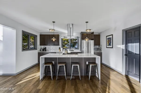 a kitchen with stainless steel appliances a dining table chairs and wooden floor