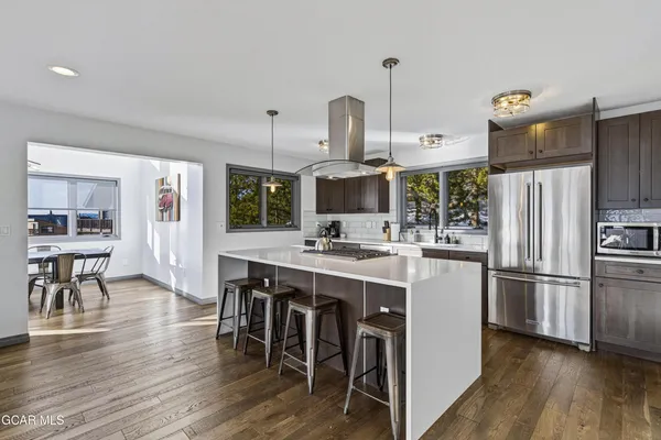 a kitchen with stainless steel appliances a kitchen island hardwood floor sink stove and wooden cabinets