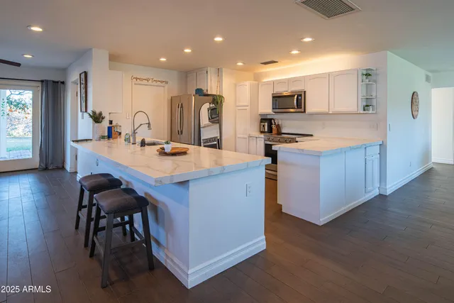 a kitchen with stainless steel appliances a microwave a sink a stove a refrigerator a counter top space and cabinets