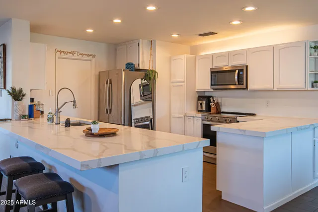 a room with stainless steel appliances kitchen island granite countertop a sink and cabinets