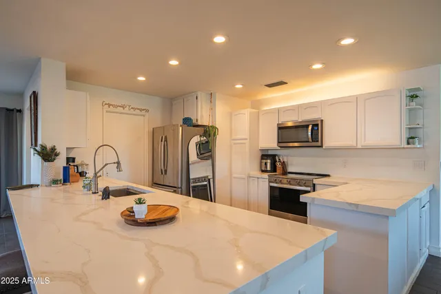 a room with kitchen island a white furniture a fireplace and a view of kitchen