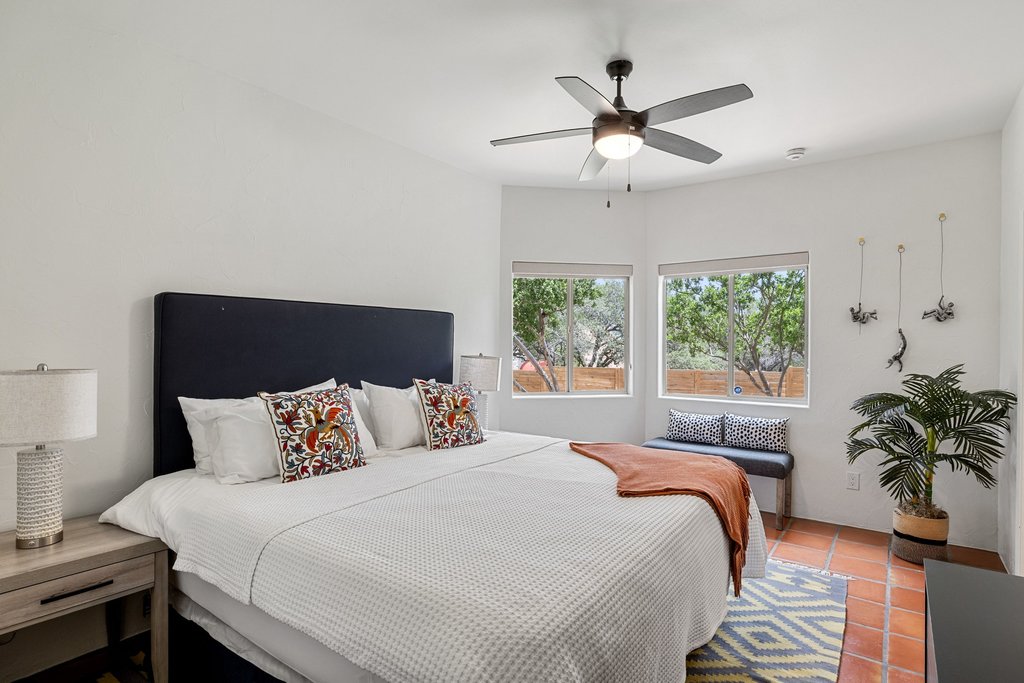 716 North Commons Ford Road Austin, TX 78733 - Photo 13 of 30 Bedroom featuring a ceiling fan with integrated lighting, wood-finish flooring, and multiple windows with views of natural greenery