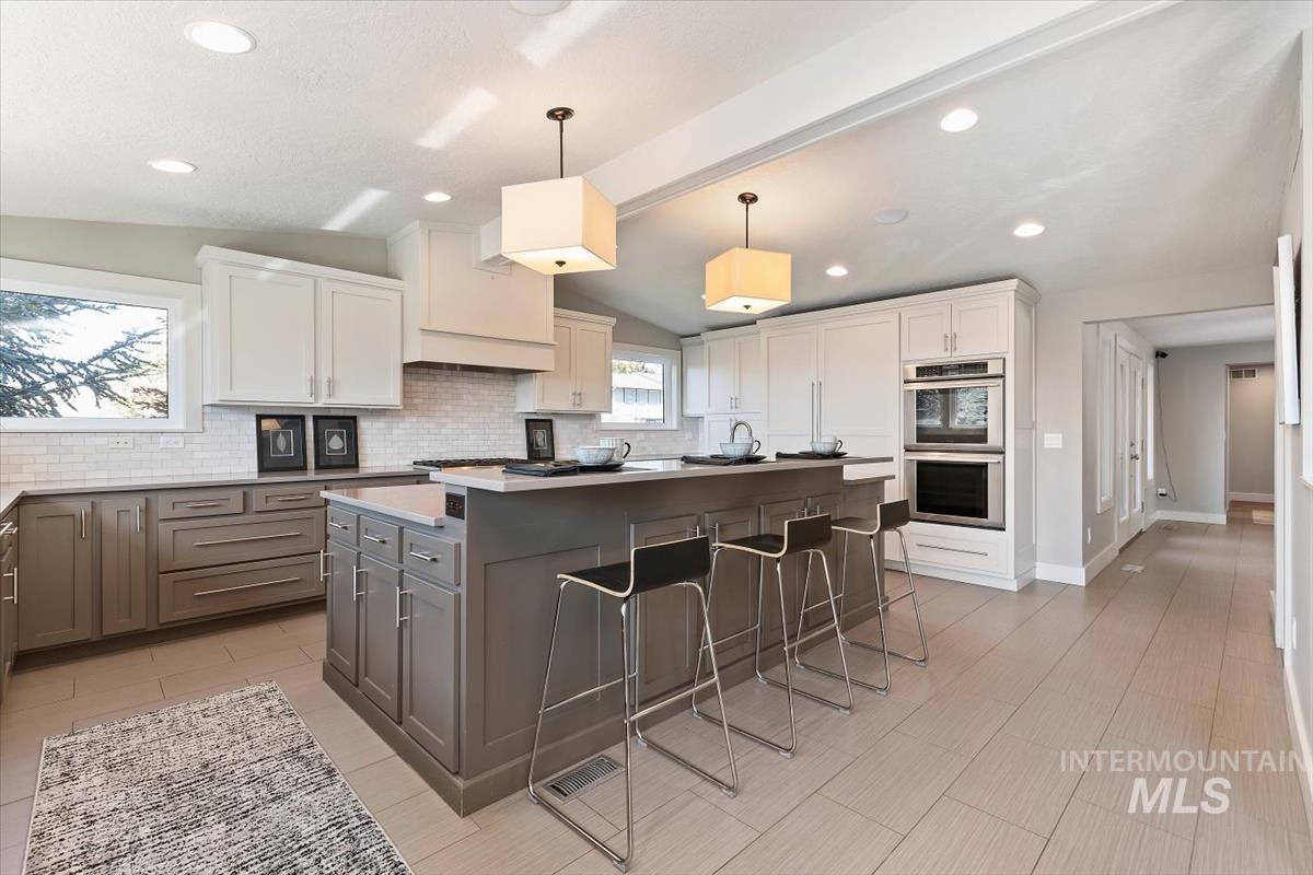 709 East Braemere Road Boise, ID 83702 - Photo 8 of 50 Kitchen featuring a central island with seating, built-in stainless steel appliances, two-tone cabinetry, a tile backsplash, and recessed lighting