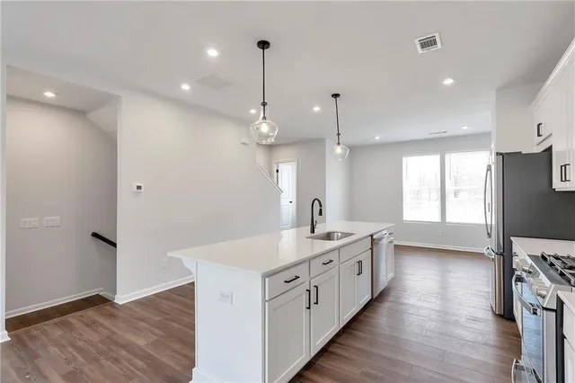 a kitchen with stainless steel appliances kitchen island wooden floors wooden cabinets and entryway