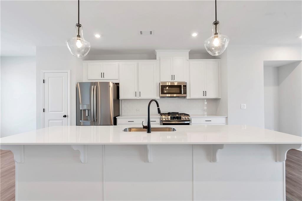 2244 Whistler Way Northeast Lawrenceville, GA 30043 - Photo 12 of 25 a kitchen with kitchen island granite countertop stainless steel appliances a refrigerator a stove a sink and white cabinets