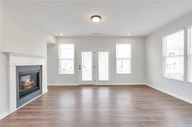 a view of an empty room with wooden floor fireplace and a window