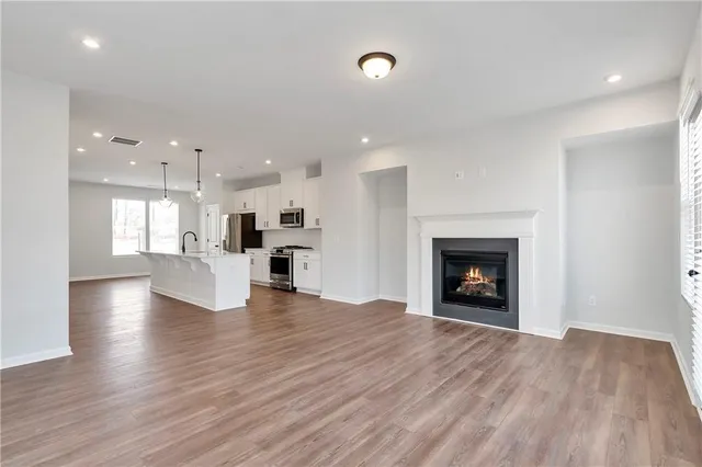 a view of an empty room and a kitchen with electric equipment