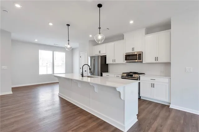 a kitchen with stainless steel appliances a white stove top oven a sink dishwasher and a refrigerator with wooden floor