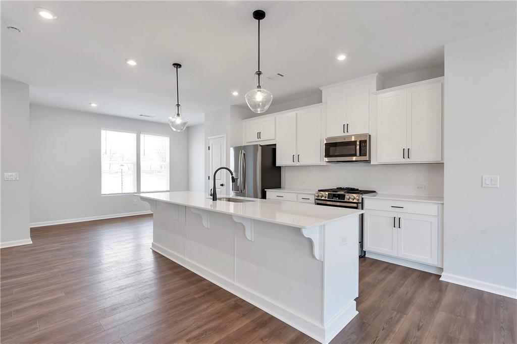 2244 Whistler Way Northeast Lawrenceville, GA 30043 - Photo 9 of 25 a kitchen with stainless steel appliances a white stove top oven a sink dishwasher and a refrigerator with wooden floor