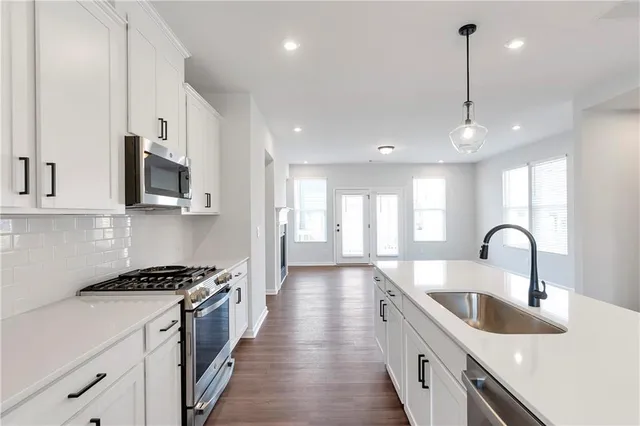 a kitchen with stainless steel appliances a sink a stove top oven a counter space and cabinets