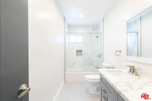 a bathroom with a granite countertop sink a toilet and a large mirror