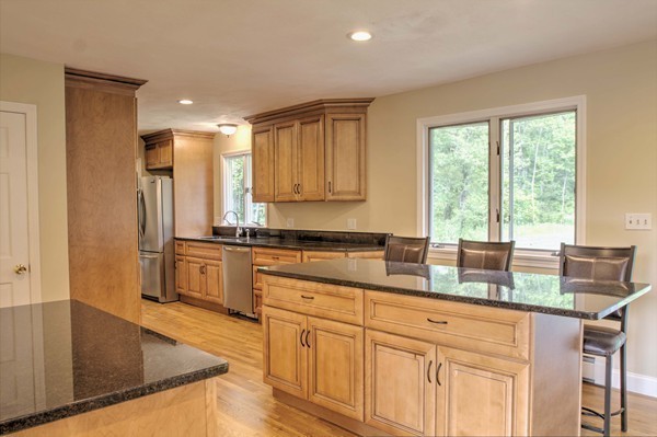 23 Hunt Road Westford, MA 01886 - Photo 4 of 27 a kitchen with granite countertop a stove a sink a refrigerator and blue cabinets with wooden floor