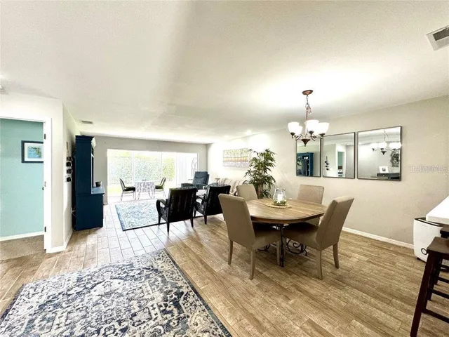 a living room with furniture a rug and a dining table with wooden floor