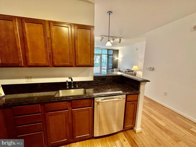 a view of kitchen and empty room with wooden floor