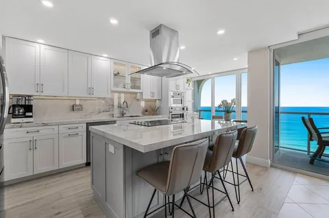 a kitchen with stainless steel appliances kitchen island a table chairs in it and white cabinets