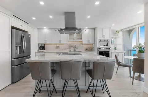 a kitchen with stainless steel appliances kitchen island granite countertop a kitchen island and chairs in it