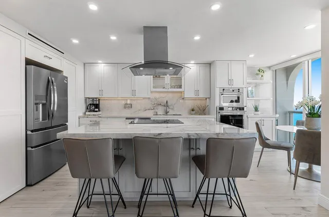 a kitchen with stainless steel appliances kitchen island granite countertop a kitchen island and chairs in it