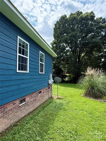 a backyard of a house with plants and a large tree