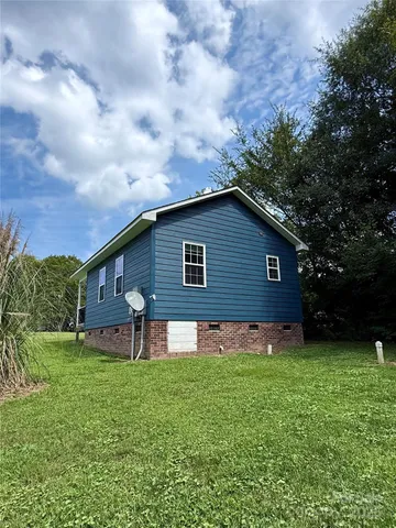 a brick house with a big yard and large trees