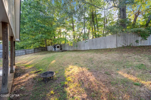 a view of a backyard with large trees and wooden fence