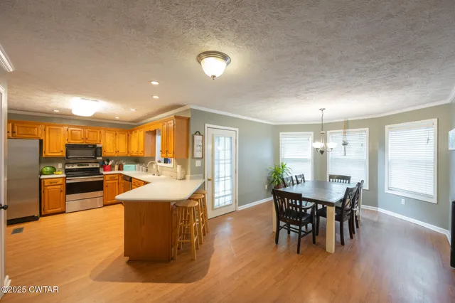 a dining hall with stainless steel appliances granite countertop a stove and a dining table with kitchen view