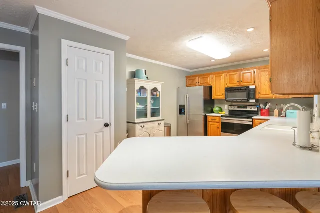 a kitchen with stainless steel appliances a stove a refrigerator a sink dishwasher with a dining table and chairs with wooden floor