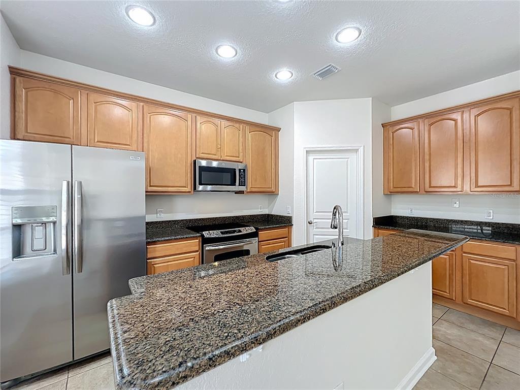 12930 Vennetta Way Windermere, FL 34786 - Photo 11 of 38 a kitchen with stainless steel appliances granite countertop a refrigerator a stove and a sink with wooden floor