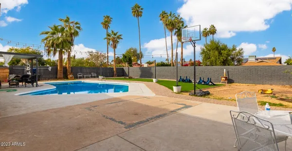 a view of a swimming pool with lawn chairs and a big yard