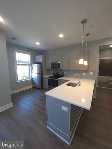 a kitchen with kitchen island a sink dishwasher a stove and a refrigerator with wooden floor