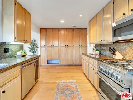 a large kitchen with stainless steel appliances granite countertop a stove a sink and a refrigerator