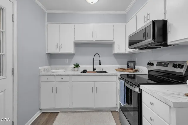 a kitchen with stainless steel appliances granite countertop grey cabinets a stove a sink and dishwasher