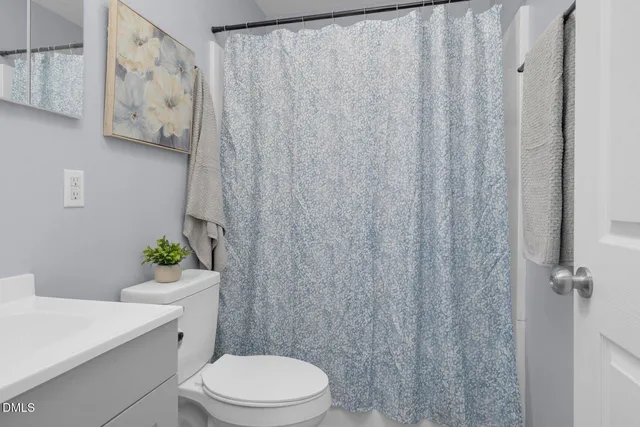 a white toilet sitting next to a white curtain