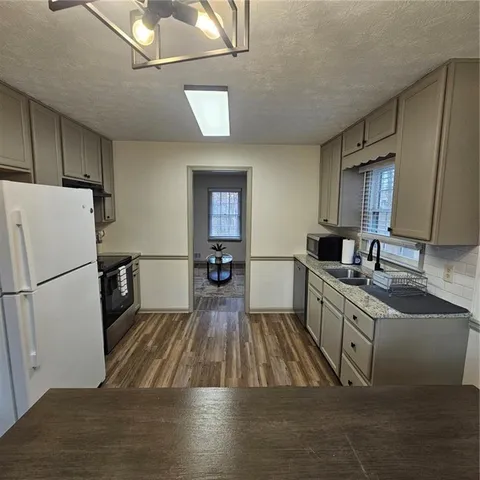 a kitchen with sink a refrigerator and wooden floor