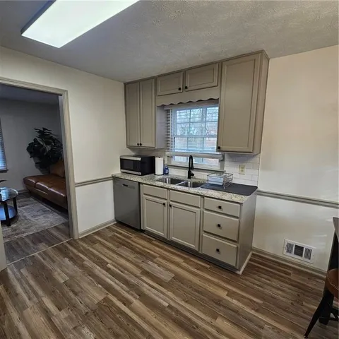 a kitchen with granite countertop a sink stainless steel appliances and cabinets