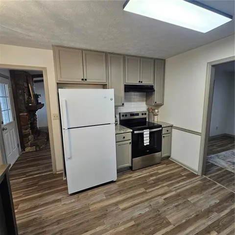 a kitchen with a refrigerator a stove top oven and wooden floor
