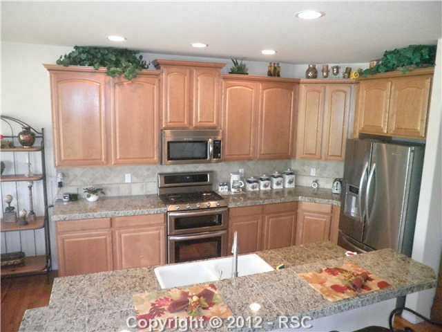 10735 Rhinestone Drive Colorado Springs, CO 80908 - Photo 2 of 16 Kitchen island has sink and quiet run dishwasher. Oven is both gas and electric with two ovens for oyur biggest dinners. Tile backsplash goes ALL the way up to oversized Maple cabinets.