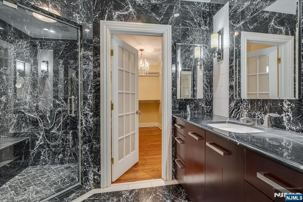 294 Oakwood Road Englewood, NJ 07631 - Photo 37 of 50 a bathroom with a granite countertop sink a mirror and shower