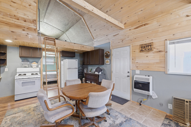 Wood-paneled walls and ceilings, wood-finish flooring, white appliances, built-in cabinetry, and a loft space with ladder access