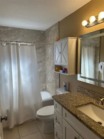 a bathroom with a granite countertop sink toilet and shower