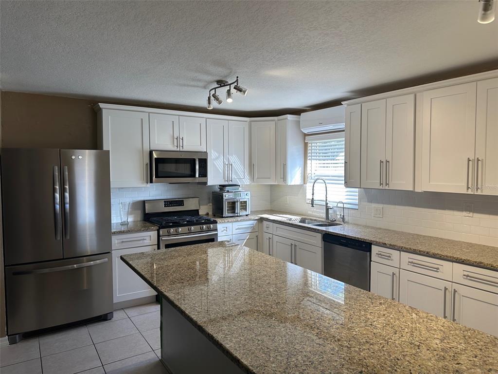 6848 Copperfield Drive New Port Richey, FL 34655 - Photo 6 of 20 a kitchen with stainless steel appliances granite countertop a sink stove microwave and refrigerator