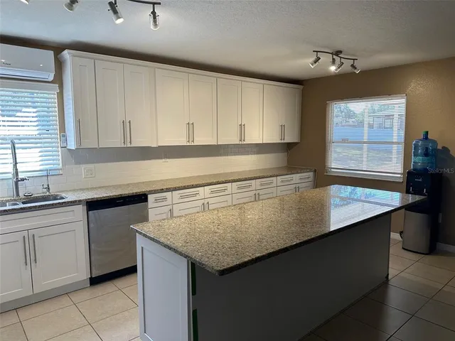 a kitchen with granite countertop a sink and white cabinets