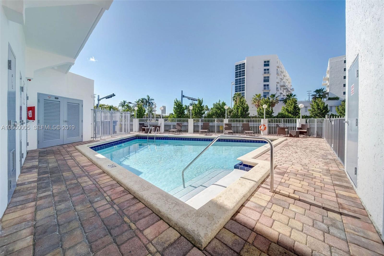 1674 Bay Road, Unit 403 Miami Beach, FL 33139 - Photo 5 of 23 a view of a swimming pool with a lawn chairs and couches